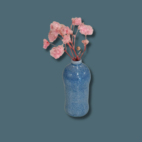 Blue speckled vase with pink flowers on a dark blue background