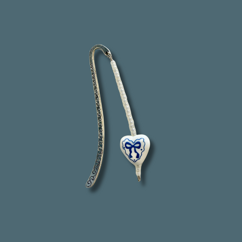 Silver bookmark with a heart-shaped tag featuring a blue bow design on a dark blue background