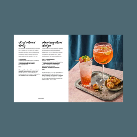 Two cocktails on a tray with a recipe card on the side against a blue background