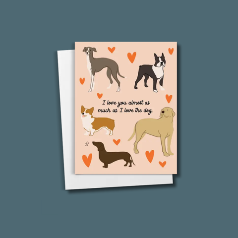 A greeting card featuring illustrated dogs and the text 'I love you almost as much as I love the dog.' on a peach background, shown with a white envelope against a slate blue backdrop.
