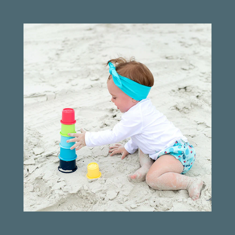 Toddler playing with cups at the beach